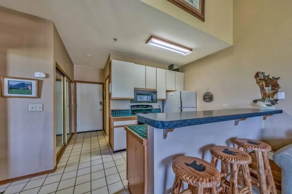 Gather around the charming kitchen bar, outfitted with unique wooden stools and inviting decor.