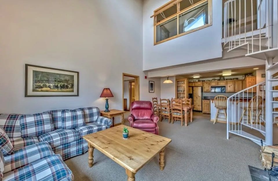 Sink into comfort with a cozy plaid sofa and a warming fireplace, perfect for relaxing after a day outdoors.