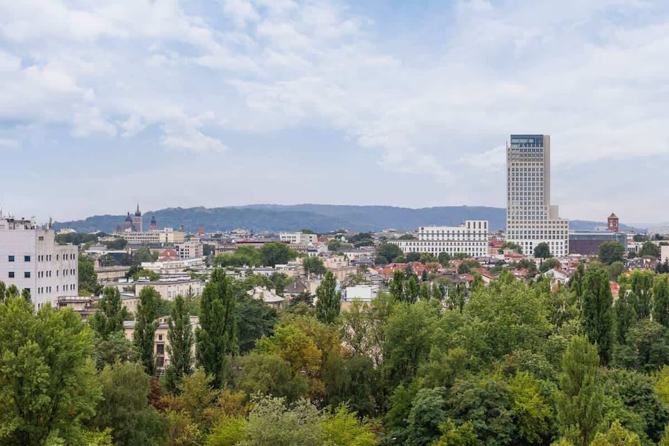 Panoramic view of a city skyline with greenery and a few tall buildings.