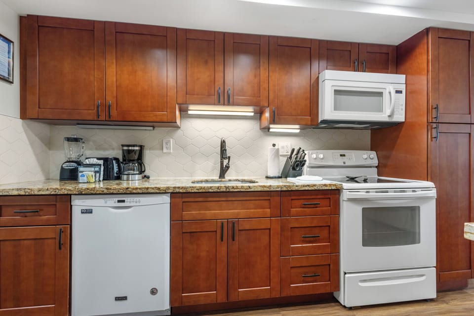 Your fully equipped kitchen features rich wood cabinetry, granite counters, and modern appliances—perfect for cooking your favorite meals or enjoying morning coffee before exploring.