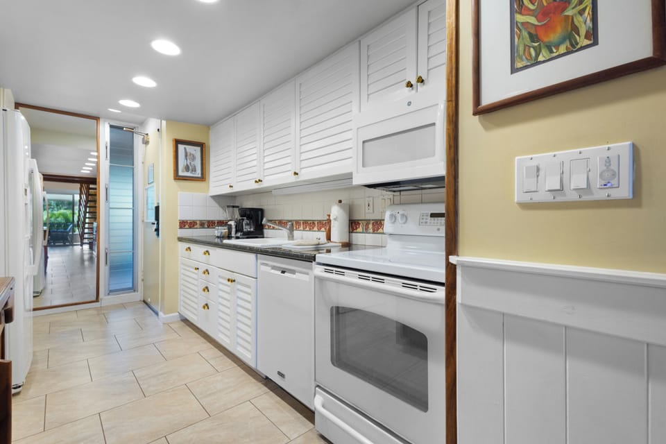 You'll love this bright, fully-equipped kitchen with white louvered cabinets, modern appliances including dishwasher and coffee maker, perfect for preparing your favorite meals during your stay.