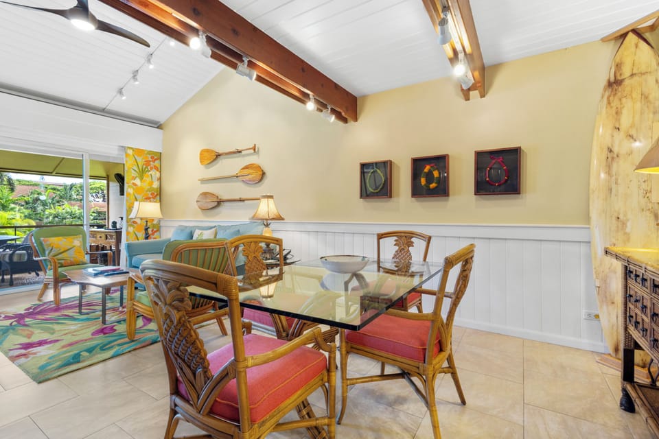 Gather around your tropical-inspired dining table where warm island vibes meet modern comfort under vaulted beamed ceilings. Relax with garden views while colorful art and unique details make every meal memorable.