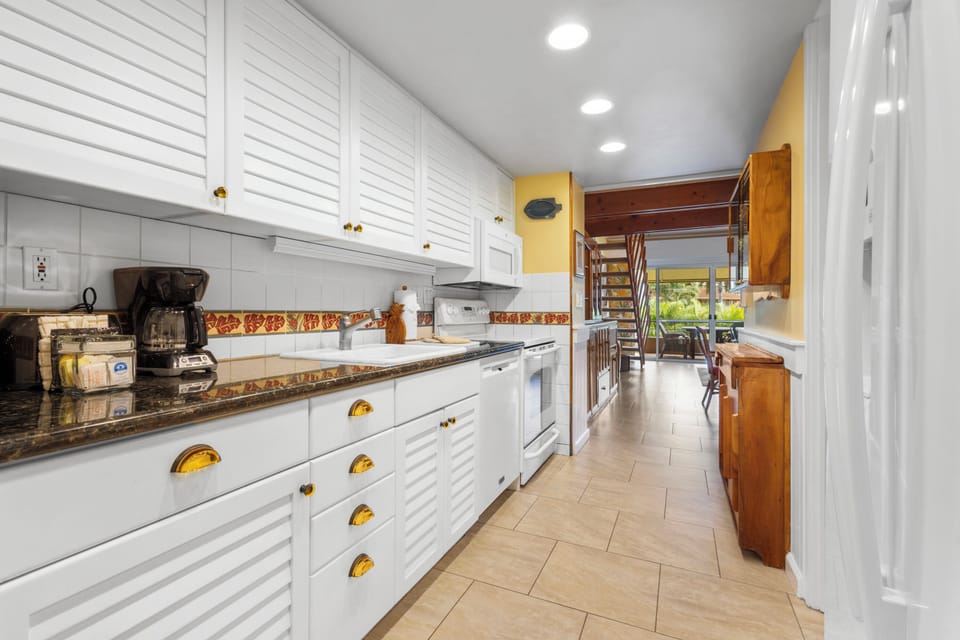 Bright, fully equipped kitchen with granite countertops, white cabinetry, and charming decorative accents—perfectly set up for cooking and gathering during your stay.