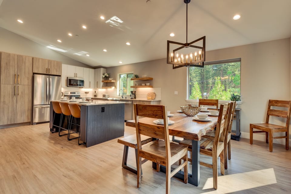 - Rustic wood dining table with seating for the group  
- Modern chandelier lighting creates a warm ambiance  
- Open kitchen and dining perfect for entertaining