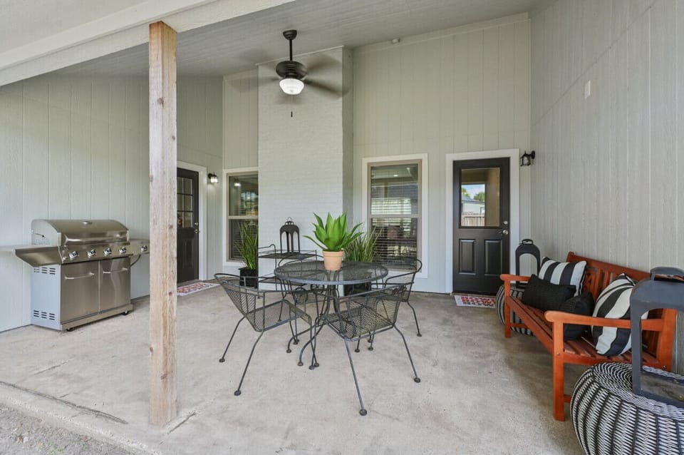 The backyard covered patio features a propane grill, table seating, and additional bench seating, perfect for hosting the whole group.