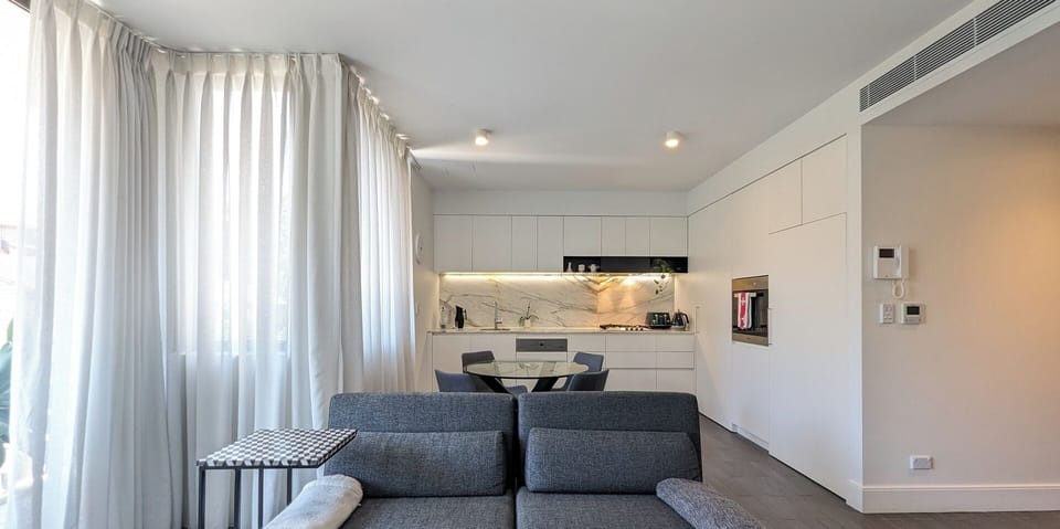 A minimalist and tidy interior showing the transition between the living and kitchen zones.