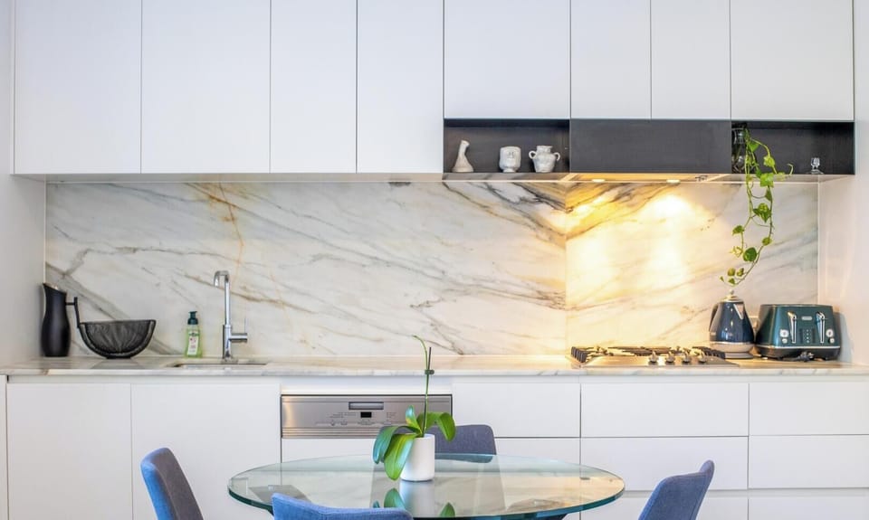 A sleek and luxurious kitchen with a stunning marble-patterned backsplash and hidden lighting.