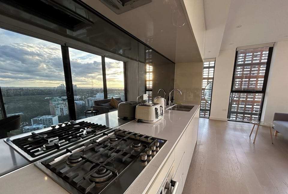 A modern kitchen workspace overlooking an open-plan living area with city views.