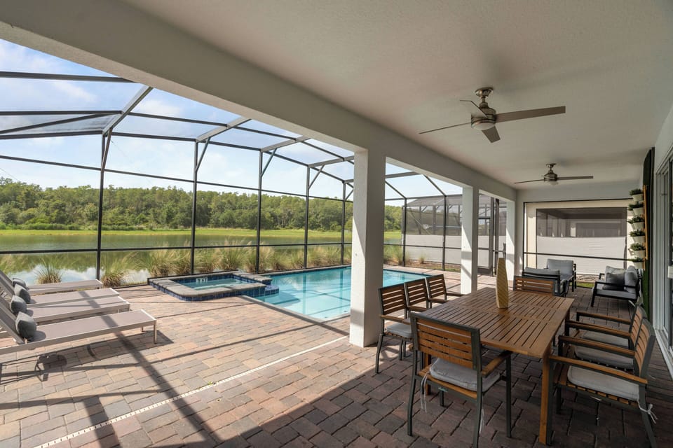 Step outside to this charming screened patio, where a spacious dining table invites al fresco meals beside a sparkling pool. Enjoy the gentle breeze from ceiling fans while soaking in stunning views of the tranquil surroundings.