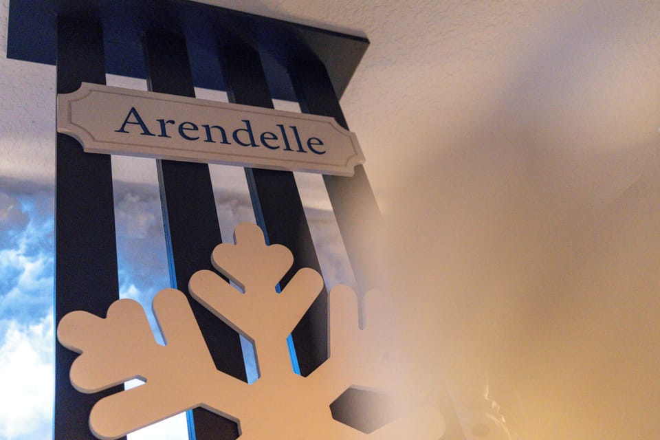 Experience a whimsical atmosphere with charming decor, playful snowflake accents, and an "Arendelle" sign that adds a fun theme. The deep blue stripes create a striking backdrop, enhancing your unique stay.