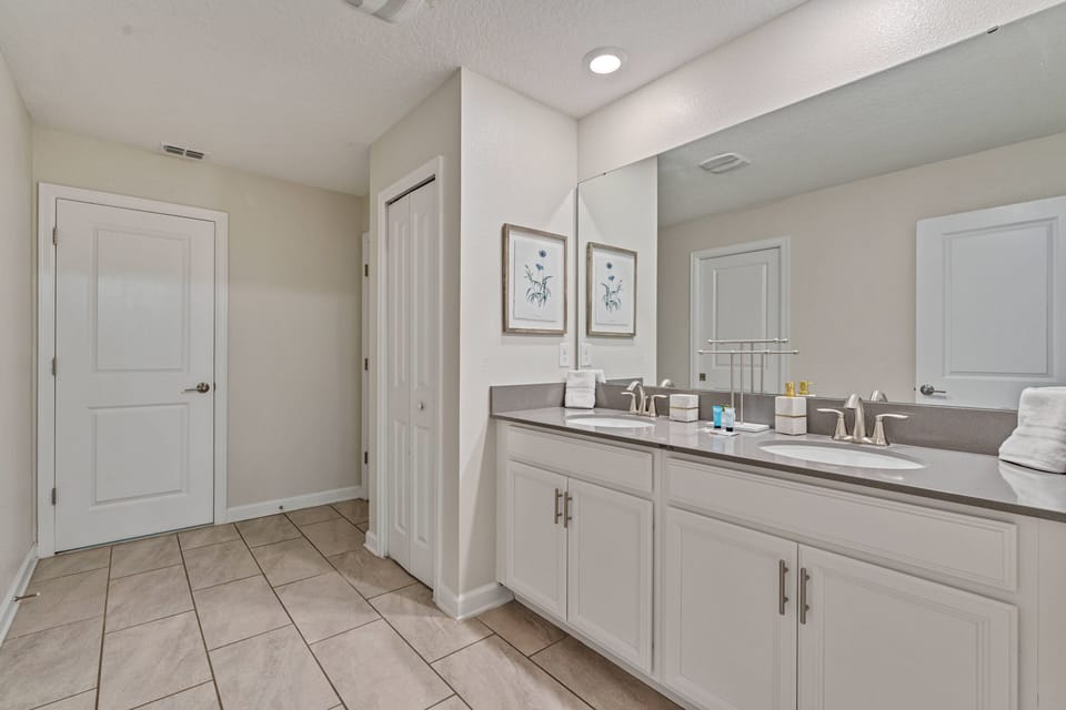 Experience a bright and inviting bathroom with a spacious double vanity, sleek countertops, and plenty of storage. The soft neutral tones and large tiles provide a clean, relaxing atmosphere for unwinding after your adventures.