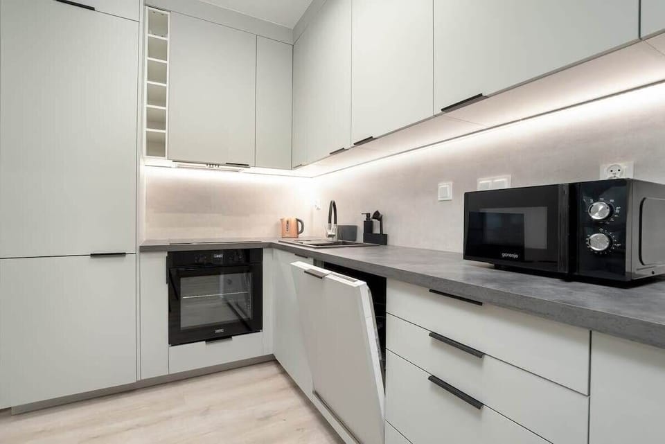 A streamlined modern kitchen with white cabinetry, integrated appliances, and a neat, practical layout.