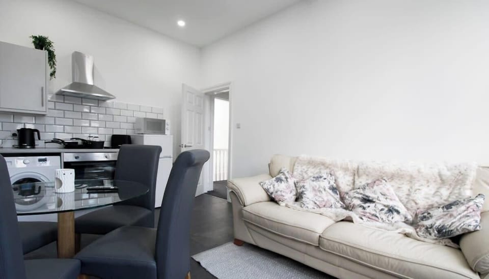 Central to the lounge find a glass round dining table with 4 grey chairs.