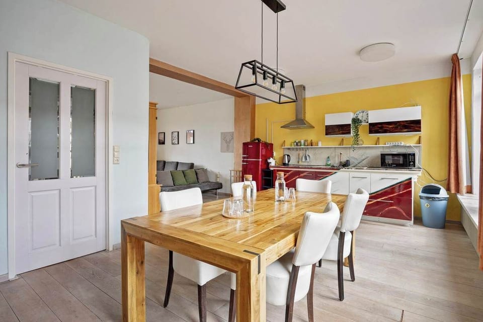 Modern kitchen and dining area with a wooden table and red-accented cabinetry