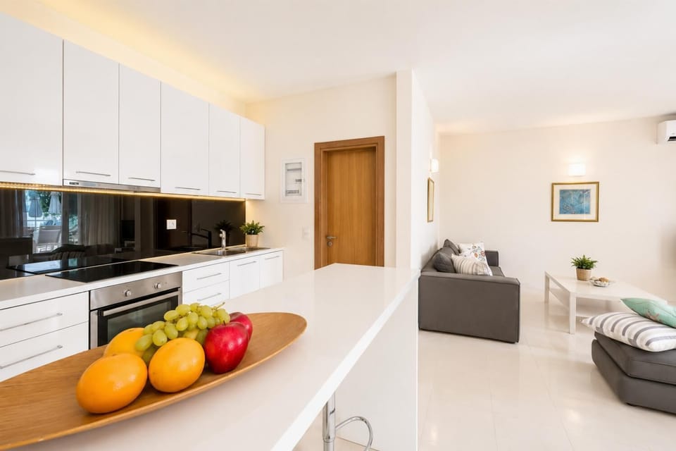 Open-plan living room with sofa, dining area, kitchen, A/C, WiFi internet, and satellite TV