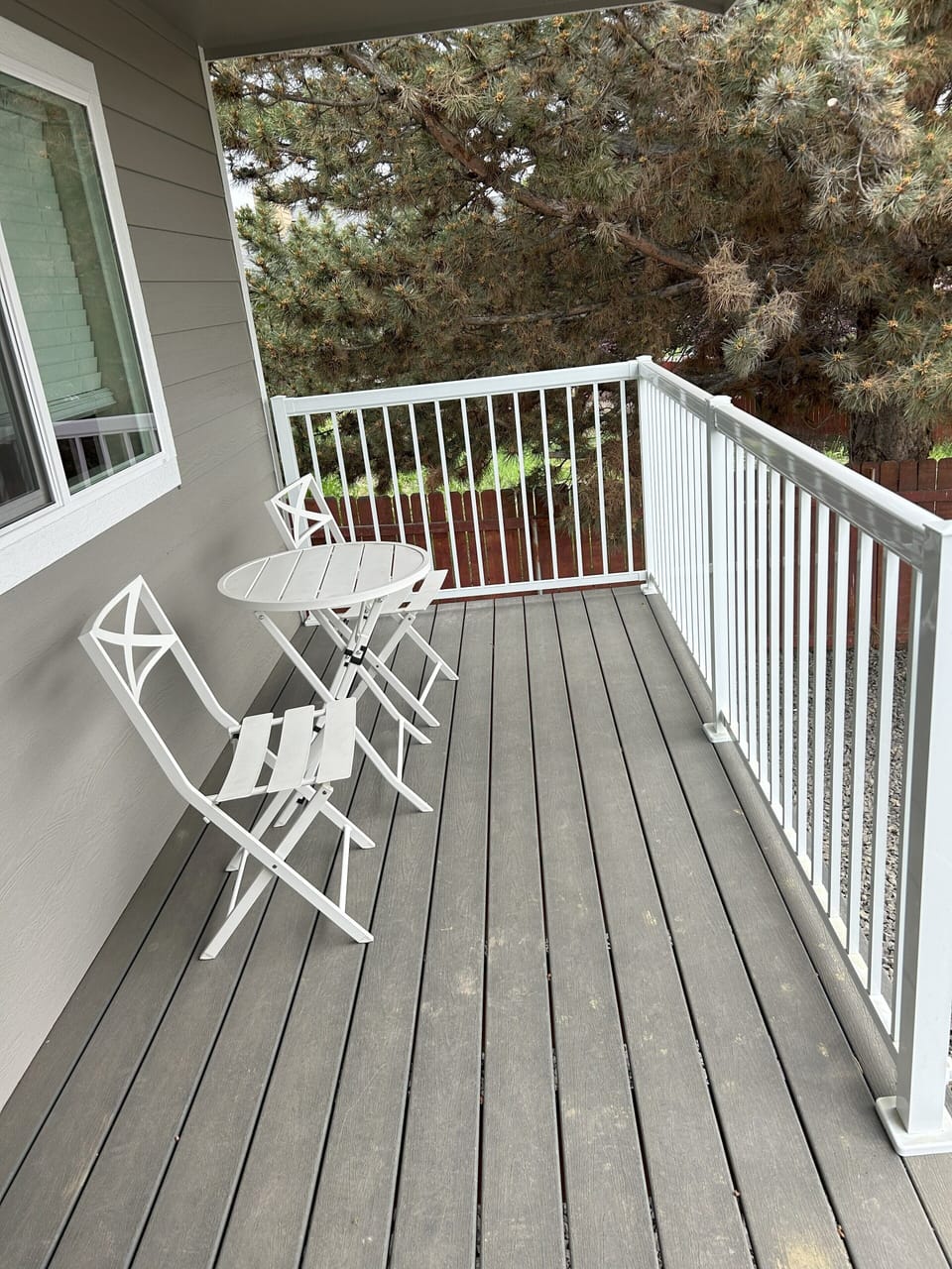 Backyard patio deck with two chairs and a table.