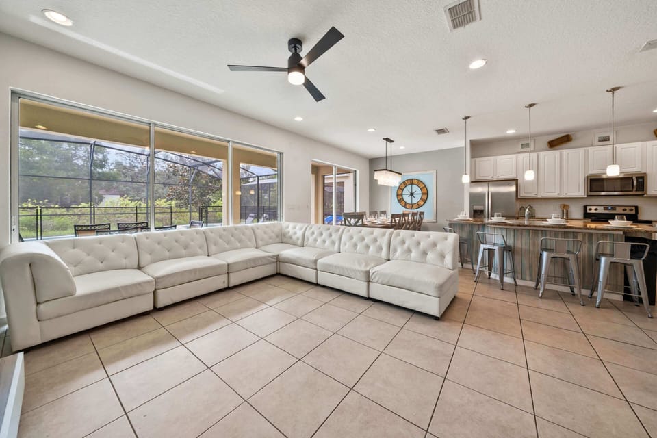 - Spacious living area with sectional sofa and open-concept design  
- Large windows bring natural light and pool views indoors  
- Perfect gathering spot in this Orlando vacation rental home