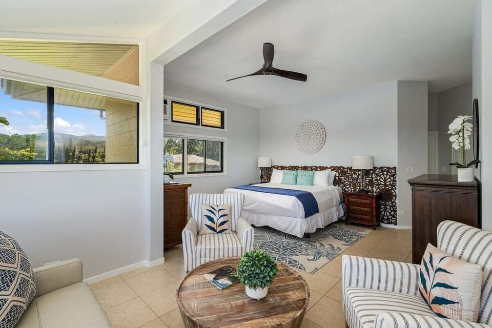 Serene bedroom with king bed, ceiling fan, seating nook, and seamless connection to the bright living spaces.