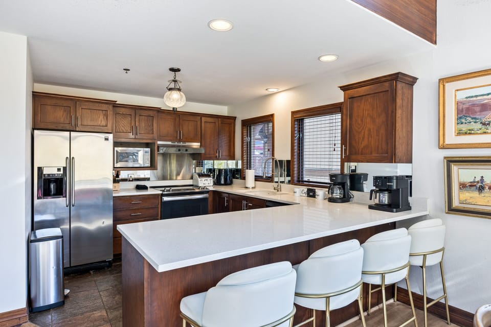 Bright and modern kitchen with stainless steel appliances, granite countertops, and ample prep space. The breakfast bar with seating is perfect for morning coffee or casual dining.