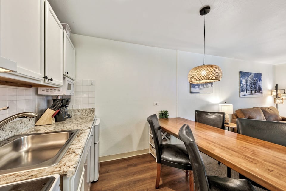 Your stylish kitchen flows into a cozy dining space with warm wood table and leather chairs, perfect for morning coffee or evening meals together.