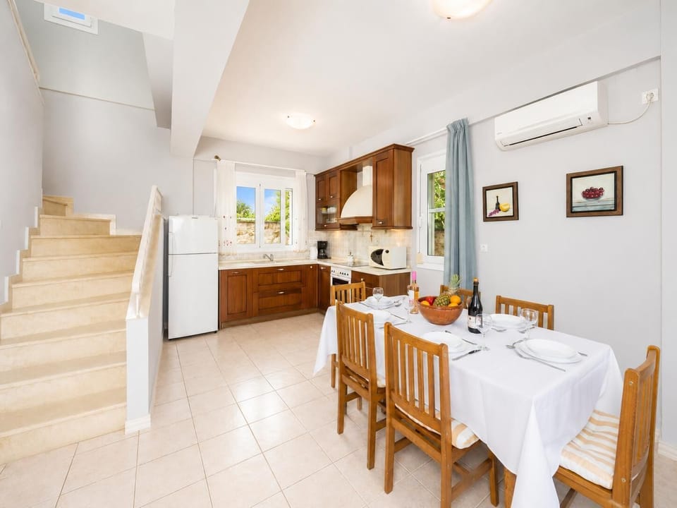 Open-plan living room with sofa, dining area, kitchen, ornamental fireplace, A/C, WiFi internet, and satellite TV