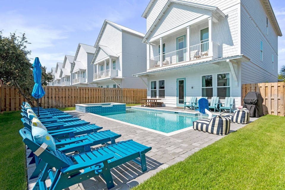 Sunlit pool deck lined w/ lounge chairs & outdoor dining for easy afternoons together