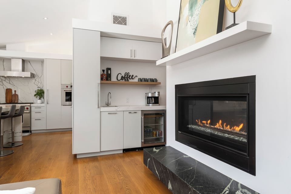 Elegant wet bar by the fireplace features a sleek countertop for drink prep