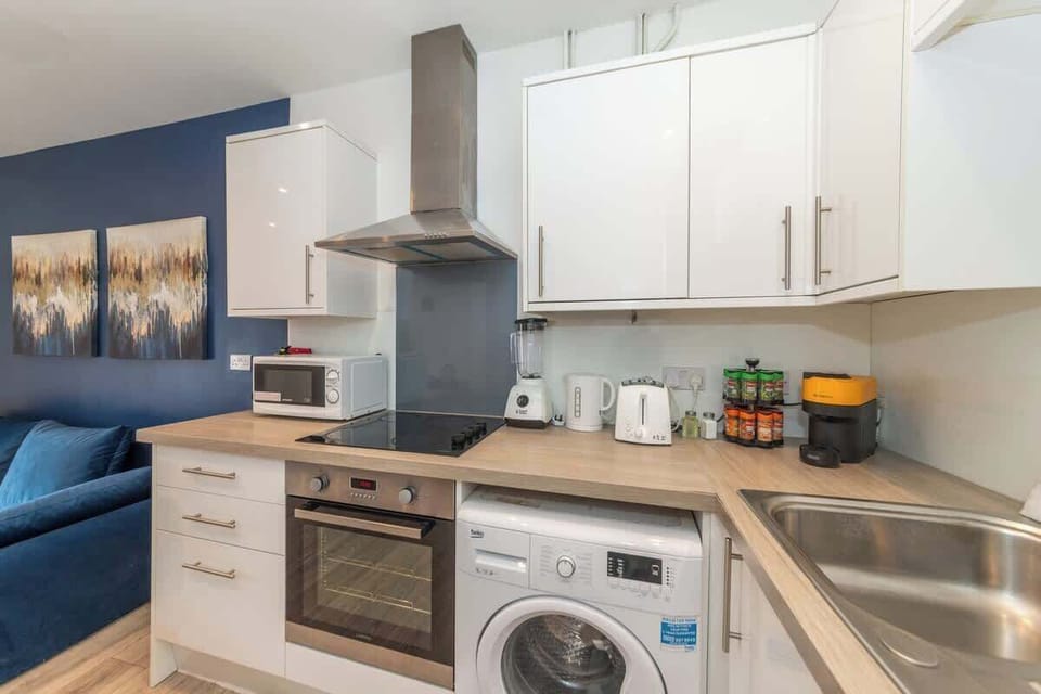 The kitchen features modern white cabinetry, stainless steel appliances, and a sleek countertop 