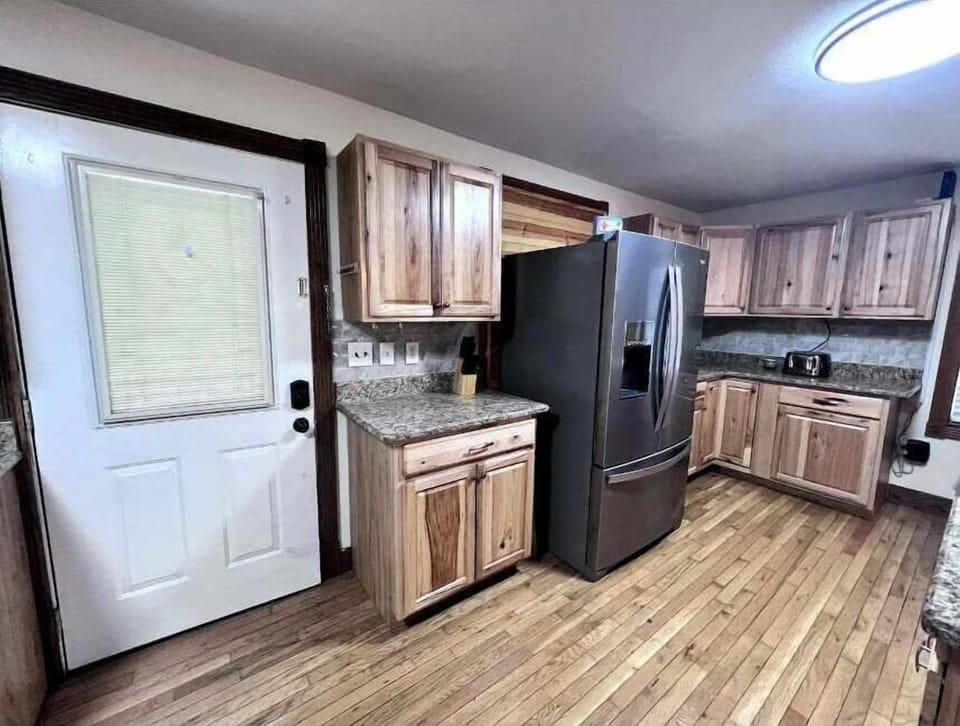 Full kitchen featuring rustic wood cabinetry, granite countertops, stainless appliances, and natural light in this Smoky Mountains vacation home.