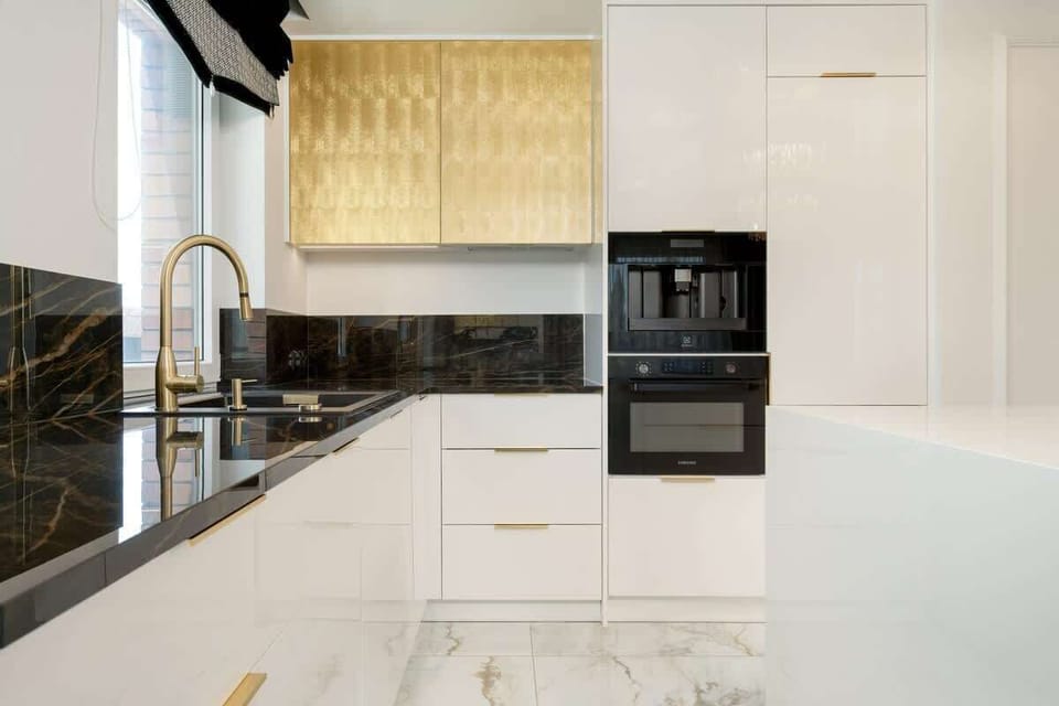 The modern kitchen with white fronts and gold details combines elegance with full functionality.