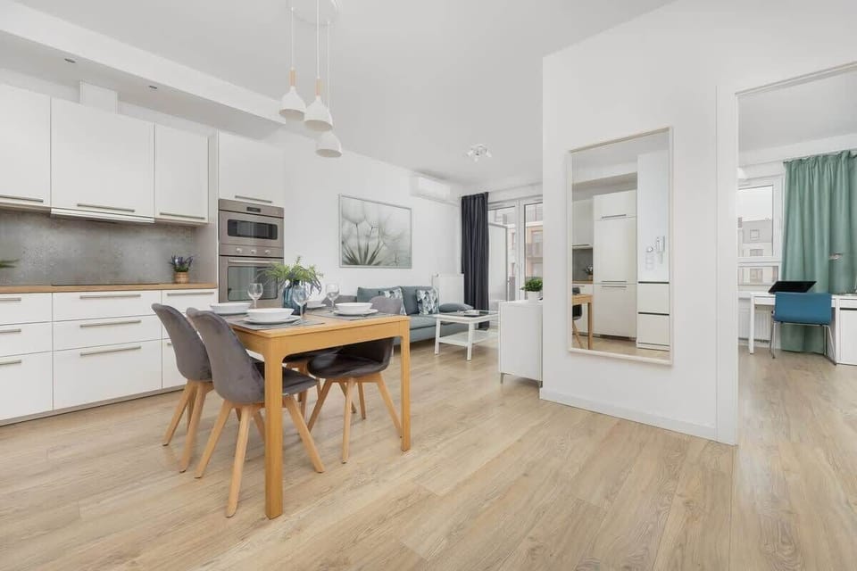 Modern kitchen with white cabinets and a central wooden dining table.