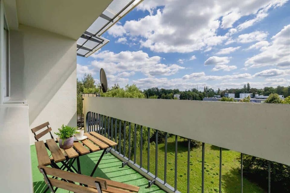 Balcony with green artificial grass, folding chairs, and open sky view.