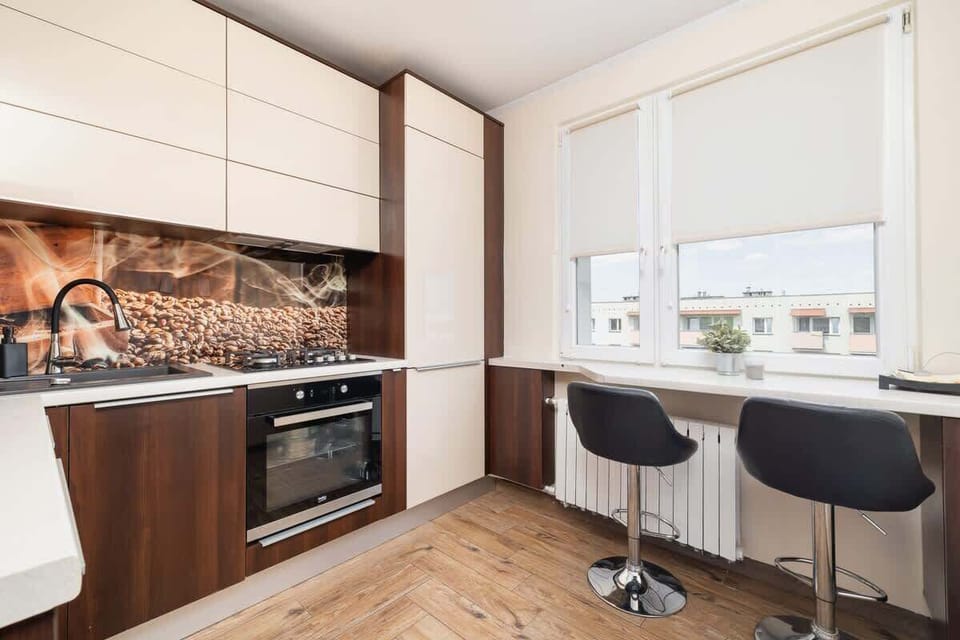 Modern kitchen with white and wood cabinets, barstools, and backsplash.