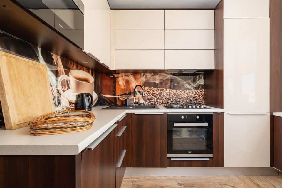 Modern kitchen with white and wood cabinets, barstools, and backsplash.