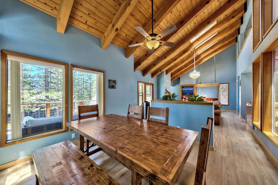Gather around your rustic dining table beneath soaring wood beams, where forest views and warm lighting create perfect moments for shared meals.