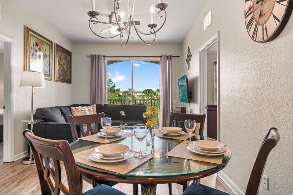 - Stylish dining area with a glass-top table set for four creating a perfect spot for meals - Dining space is beautifully illuminated by a modern chandelier adding elegance to the space - Open layout keeps the dining &living areas connected and cozy