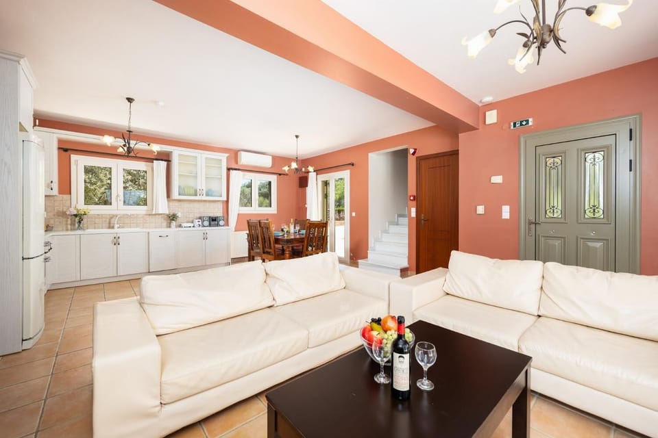 Open-plan living room with sofas, dining area, kitchen, ornamental fireplace, A/C, WiFi internet, and satellite TV