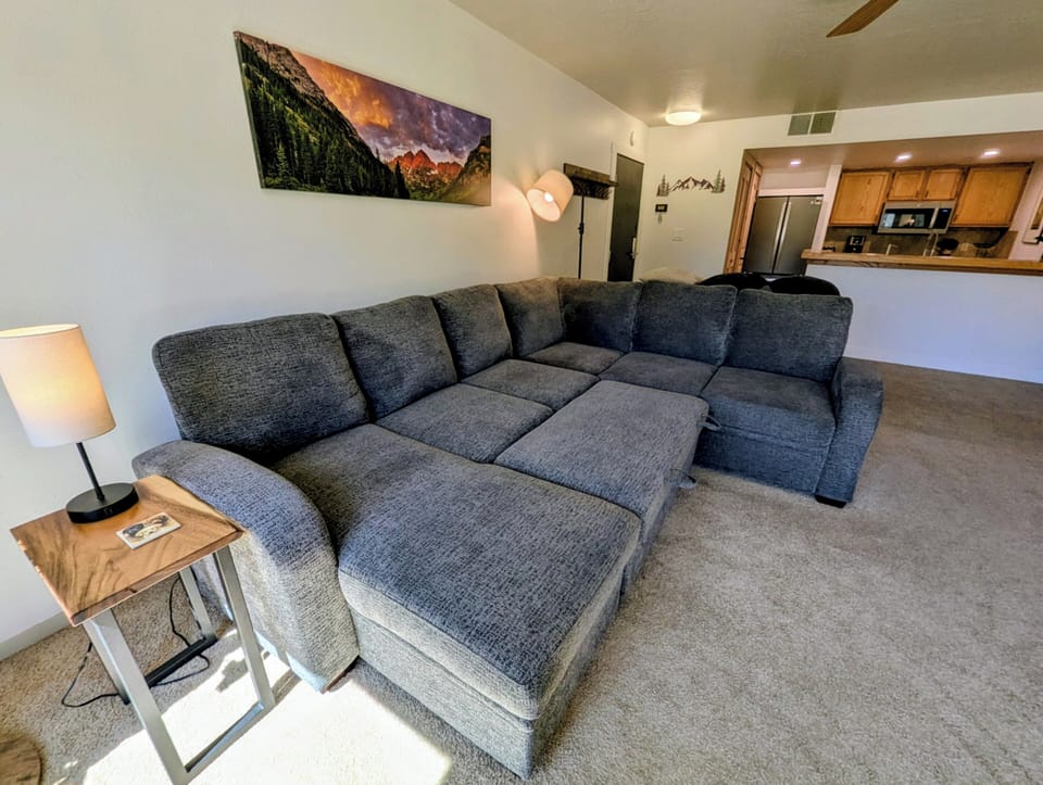 Sink into this plush sectional sofa where you can unwind after mountain adventures, with your fully equipped kitchen just steps away.