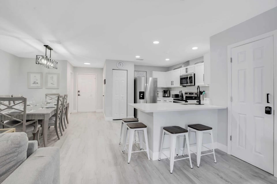 Modern kitchen and dining area with stainless steel appliances and a breakfast bar with stools