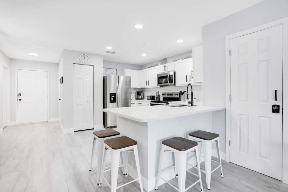 Modern kitchen with stainless steel appliances and a breakfast bar with seating.