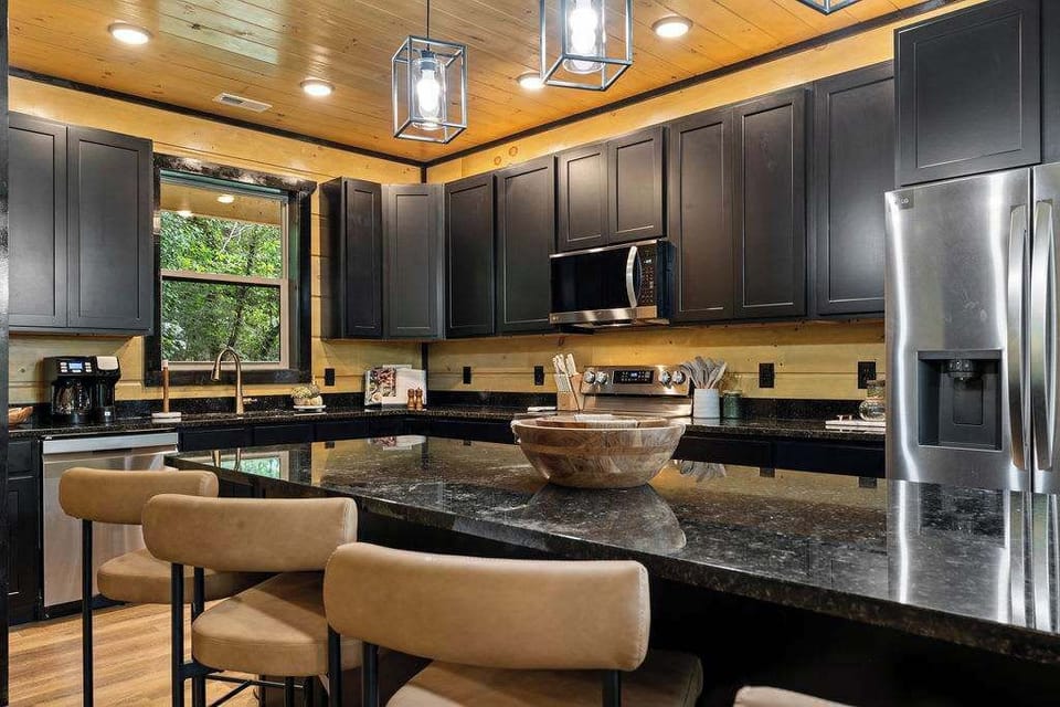 Thoughtful touches like pendant lighting and a window overlooking the greenery make this kitchen both functional and aesthetically pleasing, perfect for everything from quick breakfasts to gourmet dinners.
