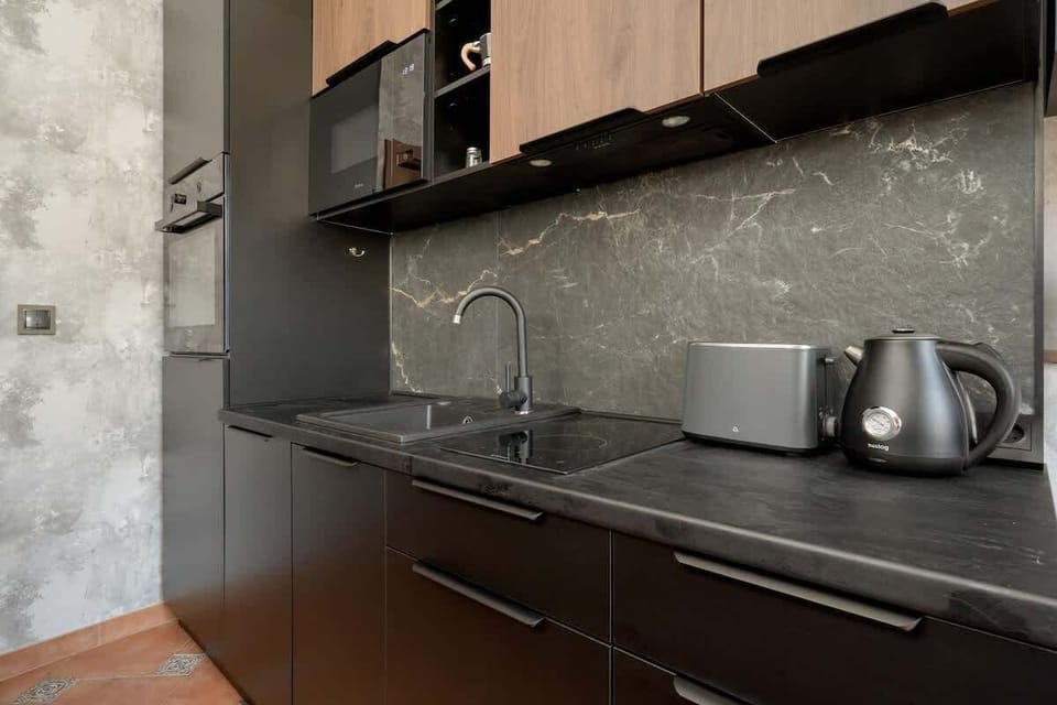 The sleek and contemporary kitchen impresses with its matte black cabinetry, marbled backsplash, and high-end appliances.