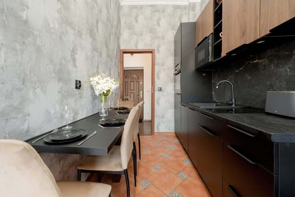 The modern kitchen pairs dark cabinetry with a warm brick-framed window, giving the space both functionality and charm.