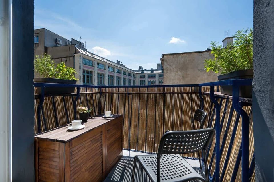 The sunny balcony is furnished with a cozy table and chairs, perfect for enjoying views over the quiet city streets.