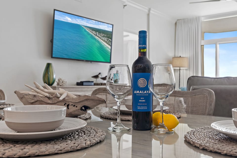 Gather around this elegant dining table with wine and coastal views on the TV, creating your perfect evening backdrop.