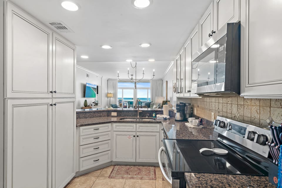 Step into your gourmet kitchen with granite countertops, premium appliances, and panoramic ocean views through the window.