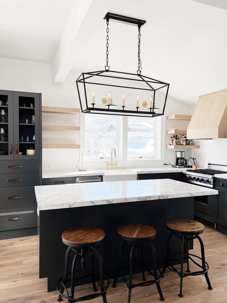 Bright kitchen features marble island countertops, Wolf range and dishwasher.