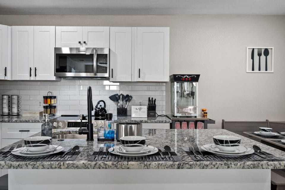 Full kitchen island countertop showing sitting area and available offerings, spice rack, popcorn machine, coffee cups