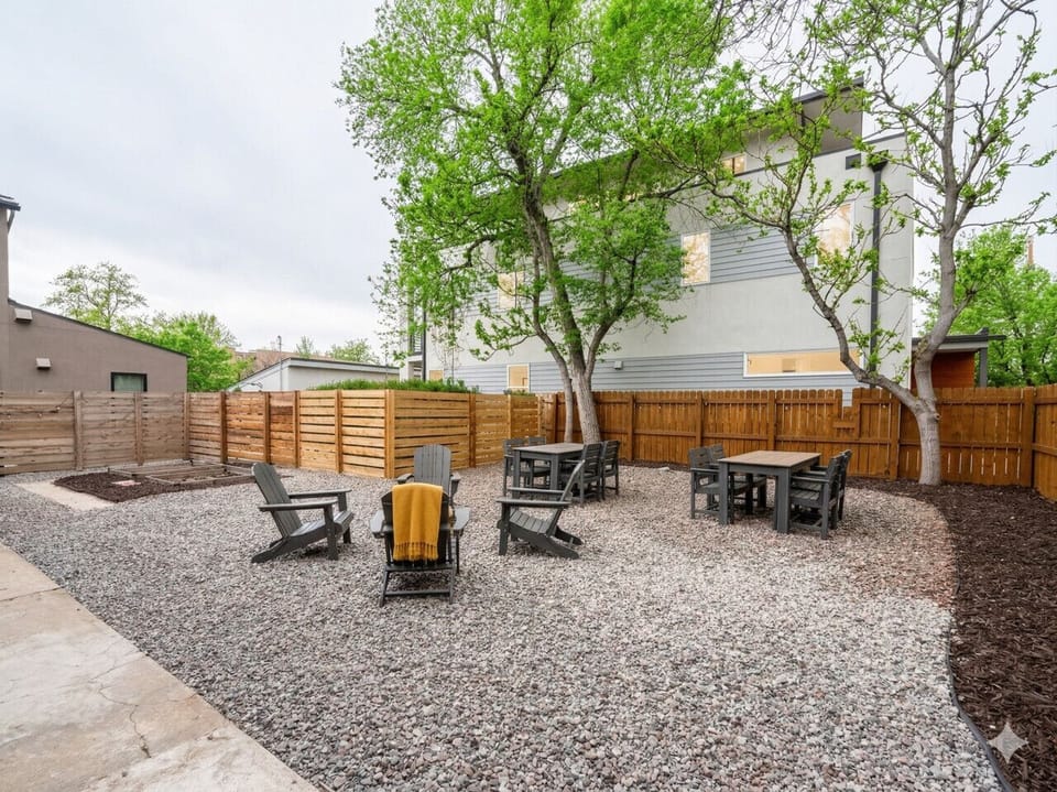 Shared fenced backyard with gravel patio, string lights, and mature shade trees