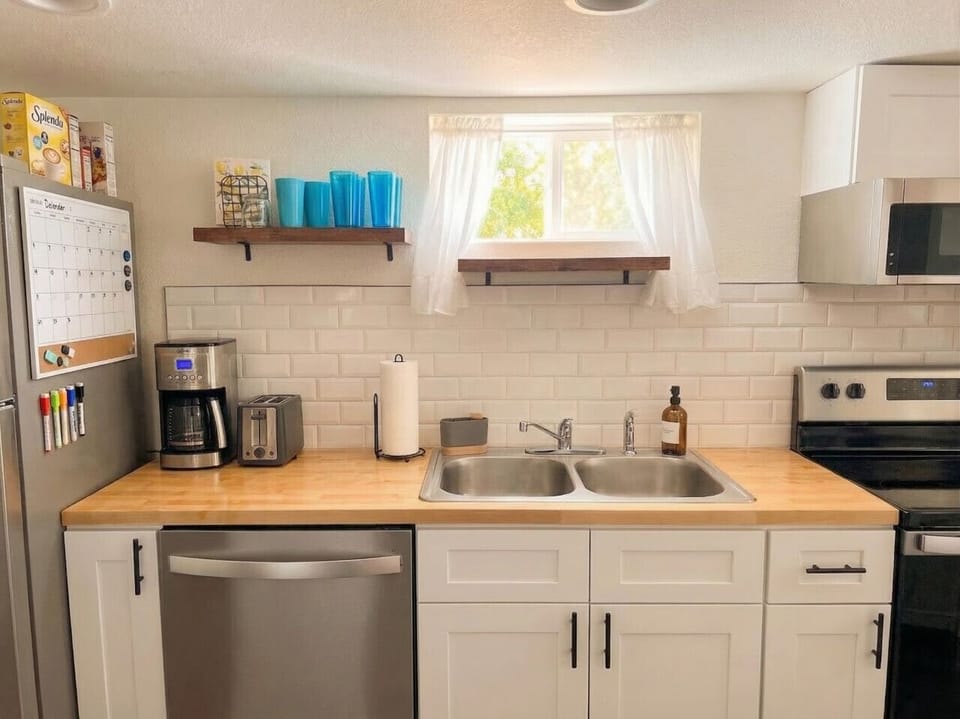 Fully equipped kitchen with butcher block counters, subway tile backsplash, dishwasher, and coffee maker -- everything you need in this Denver Highlands rental